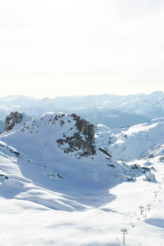 Domaine skiable enneigé et télésièges, face aux Alpes